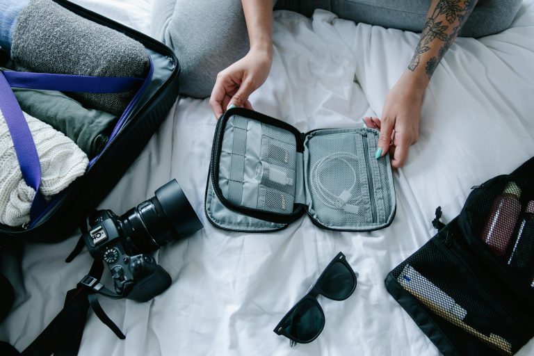 Woman efficiently packing a carry-on using 2025 travel essentials: compression cubes, folding technique, and cable organizer